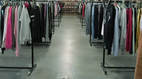 Clothing racks in a secondhand store aisle with various garments displayed on ha Stock Footage 295210053