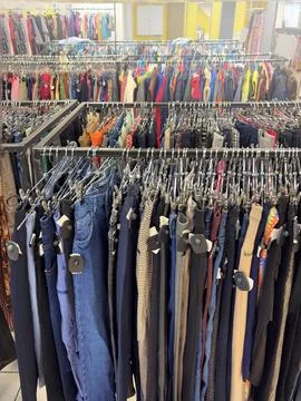 Clothing store, second hand. Rows of clothes on hangers. Multicolored Cloth.. Stock Photos