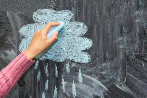 A cloud and a rain drawn with chalk on a blackboard. Stock Photos