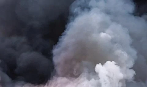 A cloud of black smoke from a fire in a building materials warehouse. Backgro Stock Photos