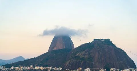 Cloud-capped mountain peak above a bustling cityscape 스톡 사진
