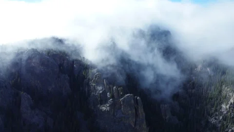 Cloud cover rolls over the Colorado mountains into the valley below Stock Footage 247363987