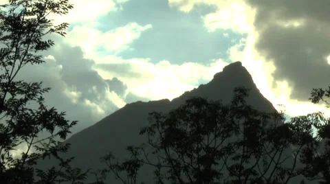 Cloud-Covered Sky with Sunlight Seeping Down above Mountains and Tree Branches 2 Stock Footage 32255952