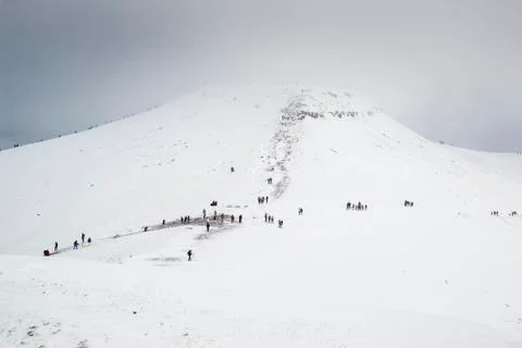 Cloud covered winter landscape of Corn Du mountain in Brecon Beacons with hikers Stock Photos