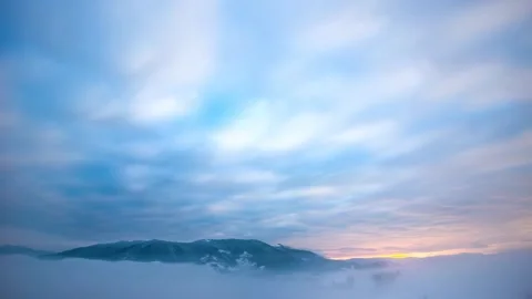 Cloud covered winter mountain peaks beneath glowing horizon Stock-Footage 341328257