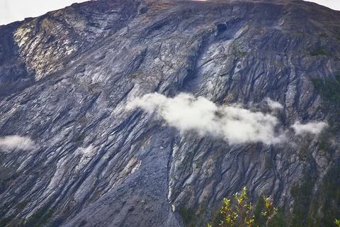 Cloud Drifting Across Rugged Mountain Face with Vegetation in Canadian 스톡 사진