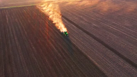 A cloud of dust rises behind a tractor plowing the ground from a bird's eye v Stock Footage 169254675