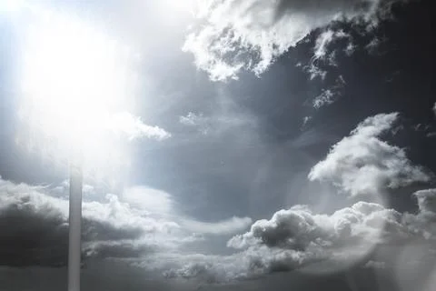 Cloud-filled sky is showcasing sun rays, lens flare and faint pole sign in flat Stock Photos