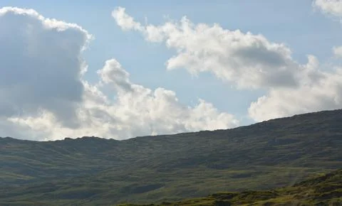 Cloud Formations Dance Above Gentle Hills During a Sunny Day Stock Photos