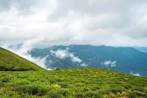 Cloud layers on mountain horizon with green grass Stock Photos