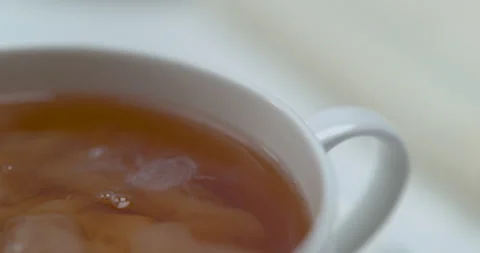 Cloud of milk moving in a white cup of tea. Close up in slow motion with a shall Stock Footage 199461258