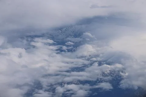 Cloud opening revealing mountain landscape below 스톡 사진