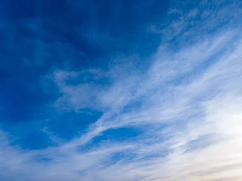 Cloud patterns in a clear sky during the early evening hours with varying s.. 스톡 사진