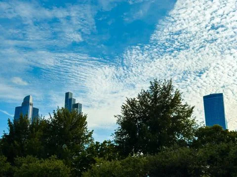 Cloud patterns fill the sky above city buildings during the day in a vibran.. 写真素材
