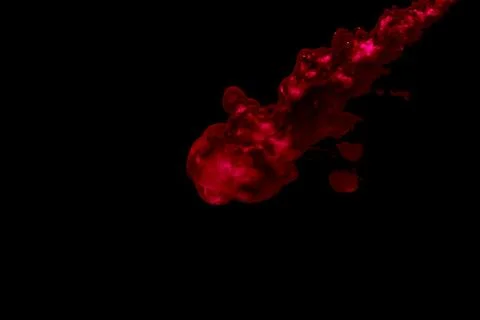 A cloud of red paint released into clear water. Isolate on a black background Stock Photos