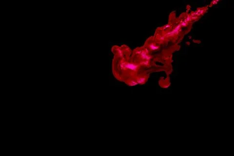 A cloud of red paint released into clear water. Isolate on a black background Stock Photos