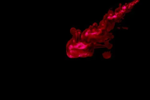 A cloud of red paint released into clear water. Isolate on a black background Stock Photos