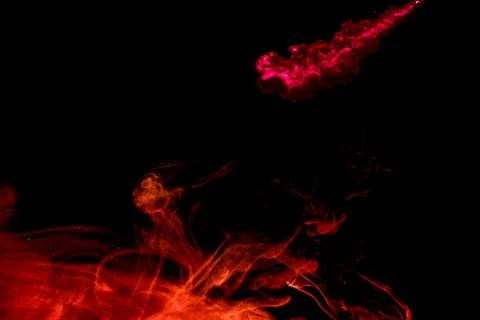 A cloud of red paint released into clear water. Isolate on a black background Stock Photos