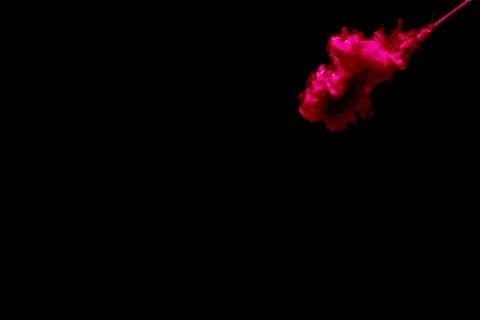 A cloud of red paint released into clear water. Isolate on a black background Stock Photos