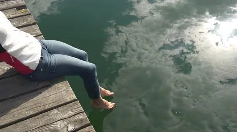 Cloud reflection in on the clear water where woman dips her feet Stock Footage 66515088