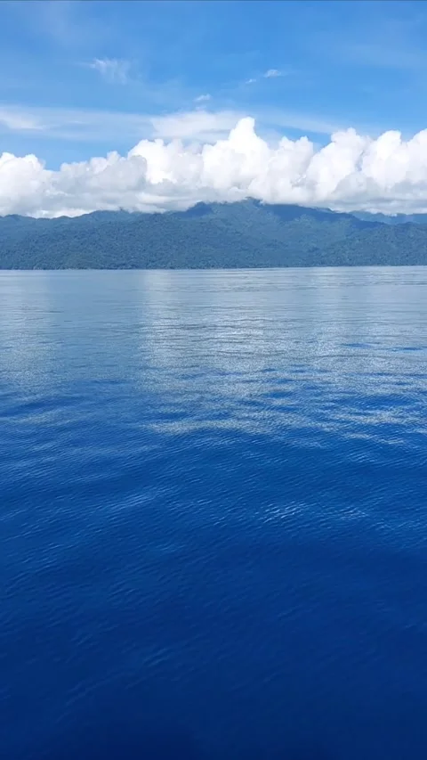 Cloud reflections on calm blue ocean with tropical mountains. Stock Footage 346215299