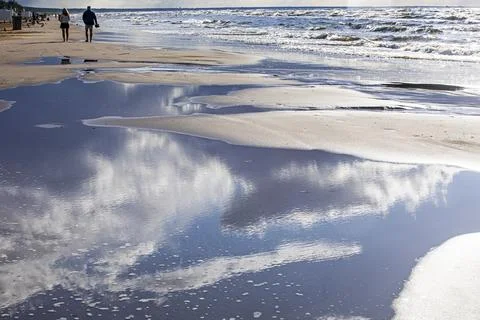 Cloud reflections at low tide on the ocean and a walk along the shore. Travel Stock Photos