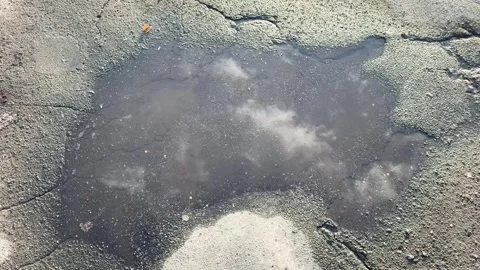 Cloud reflections in a roadside puddle on cracked asphalt, abstract texture Video stock 331331979