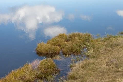 A cloud reflects itself over a small alpine lake in Dolomites at evening Stock Photos