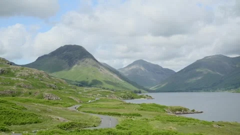 Cloud shadows racing across mountainous countryside with lakeside road Stock Footage 278450607