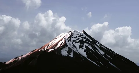 Cloud timelapse of black and snow white mountain volcano -  Cloud Cinemagraph Video stock 102564354