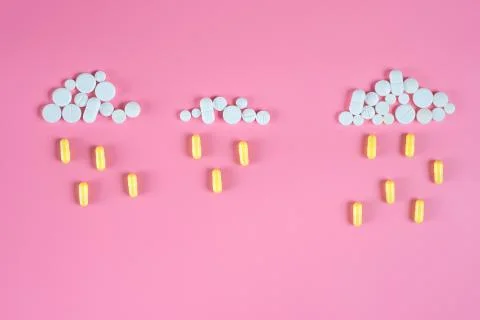 Cloud of white pills from which it is raining on pink background Stock Photos