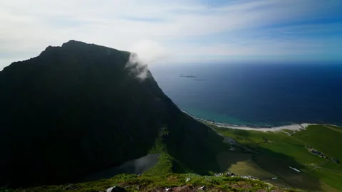 Cloud Wisp Sliding Over Sheer Mountain Above Farmland and Sea Stock Footage 340140221
