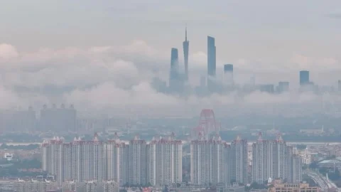 Cloud wrapped Guangzhou skyline beyond apartments in China Stock Footage 345960376