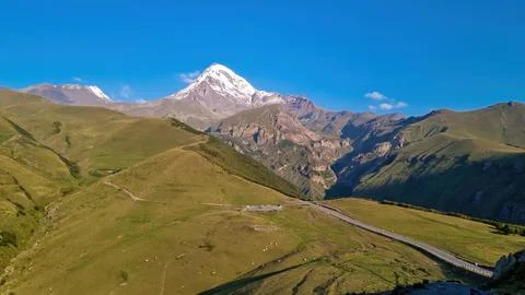 A cloudless view on Mount Kazbeg in Caucasus, Georgia. There are lush pastu.. Stock Photos