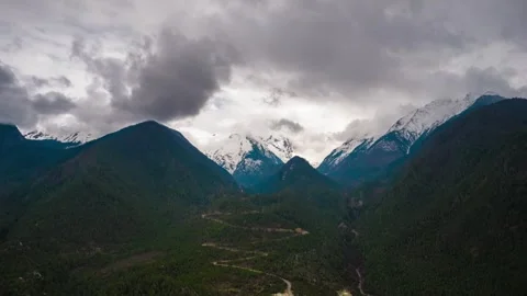 Clouds above a forested Tibetan valley and snowy mountain peaks Stock Footage 345882453