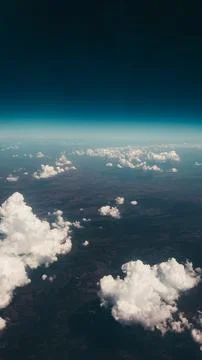 Clouds above the ground. Clouds and ground from the airplane window. Stock Photos