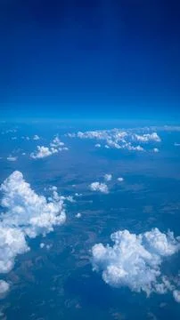 Clouds above the ground. Clouds and ground from the airplane window. Stock Photos