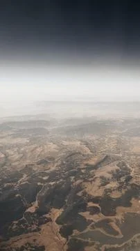 Clouds above the ground. Clouds and ground from the airplane window. Stock Photos