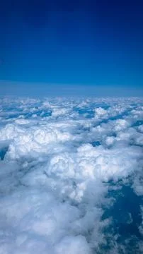 Clouds above the ground. Clouds and ground from the airplane window. Stock Photos