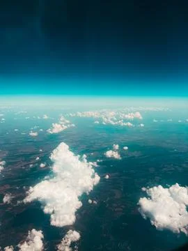 Clouds above the ground. Clouds and ground from the airplane window. Stock Photos