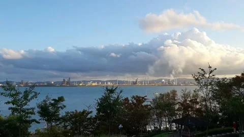 Clouds absorb smoke from factories beyond the sea. Stock Footage