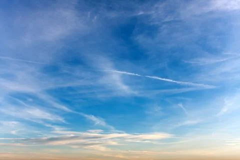 Clouds with airplane exhaust streams showing lines of pollution stretched acr Stock Photos