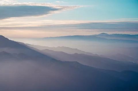 Clouds and mist rolled over the valley. Blue sky, white clouds, sunshine. Stock Photos