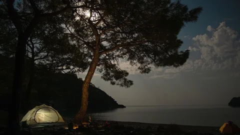 Clouds and the moon move over the bay and tent Stock-Footage 119095264