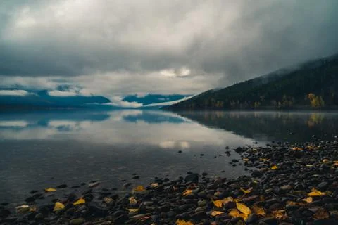 Clouds and mountains reflected in a calm lake. Stock Photos