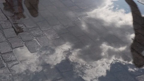 Clouds and passers-by reflect on the pavement in the puddle. Stock-Footage 93278694