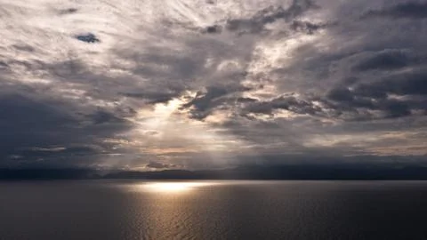Clouds and rays of sun above the sea. Bright light with sun rays and heavy Stock Photos