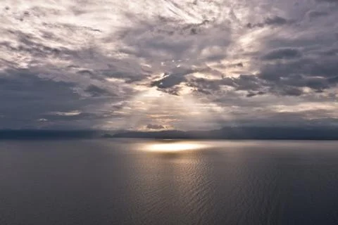 Clouds and rays of sun above the sea. Bright light with sun rays and heavy Stock Photos