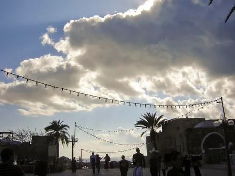Clouds and string lights with silhouetted people walking away from camera Stock Photos