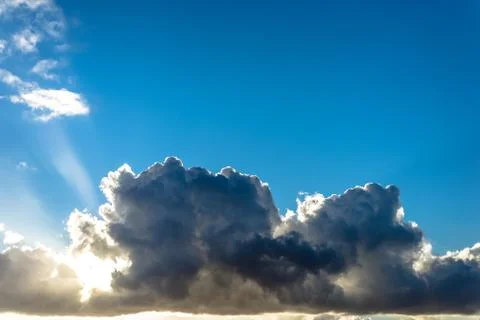 Clouds and sun in a blue sky at sunset Stock Photos